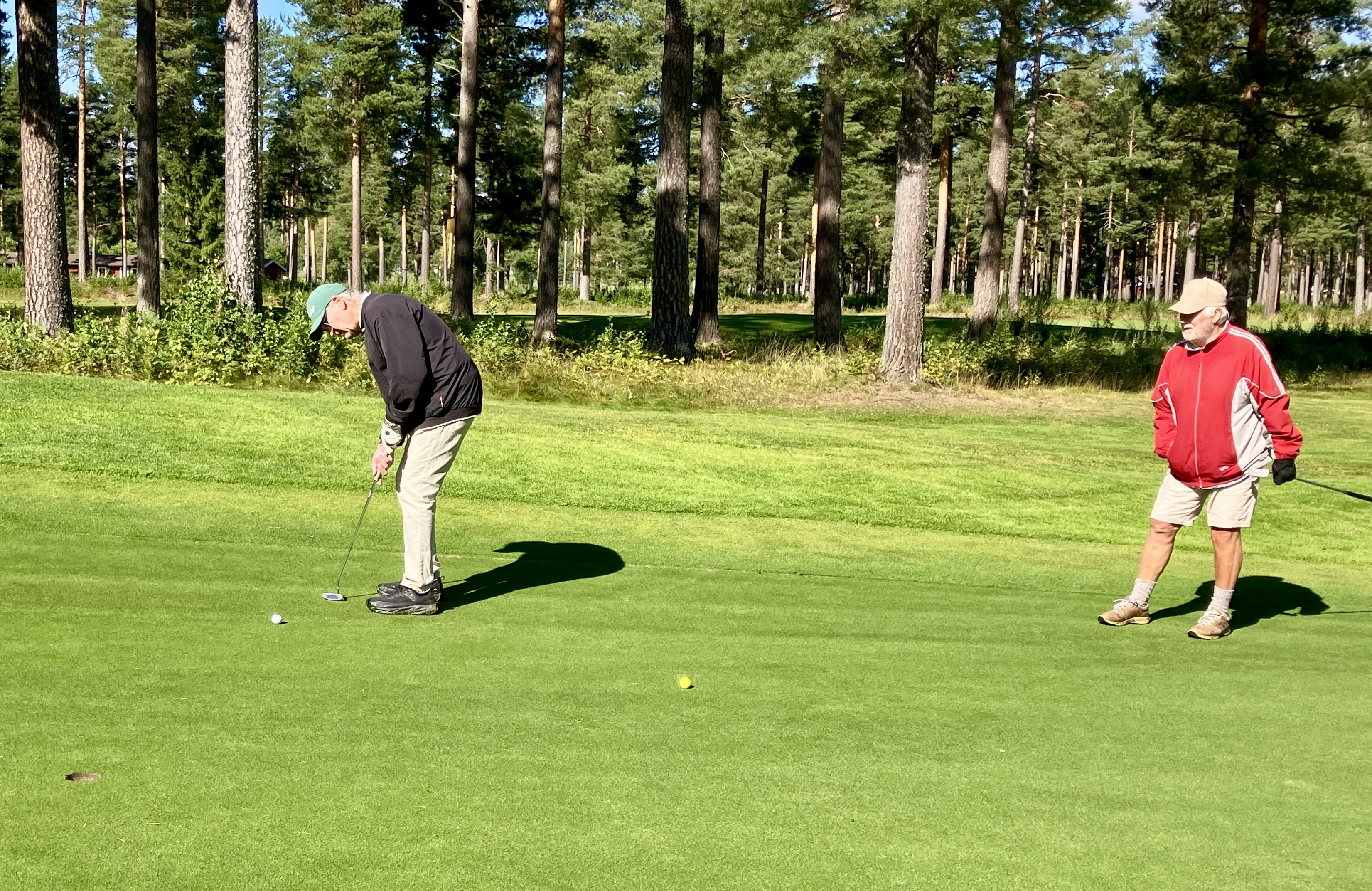 Per Borssén puttar på hål 15 medan Göran Waldermark tittar på.