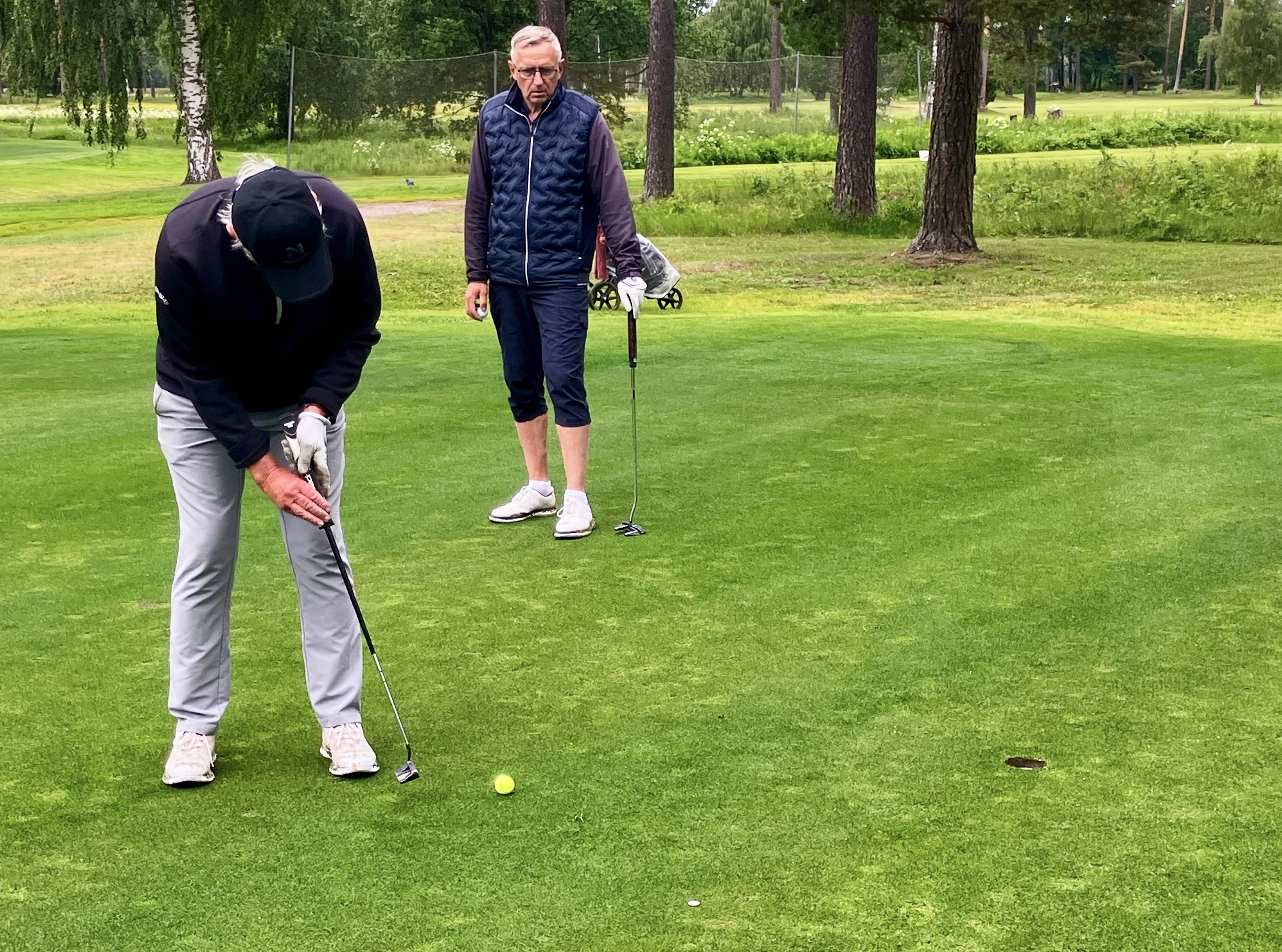 Hans Jax puttar på hål 17. under överinseende av Lars Larsson.