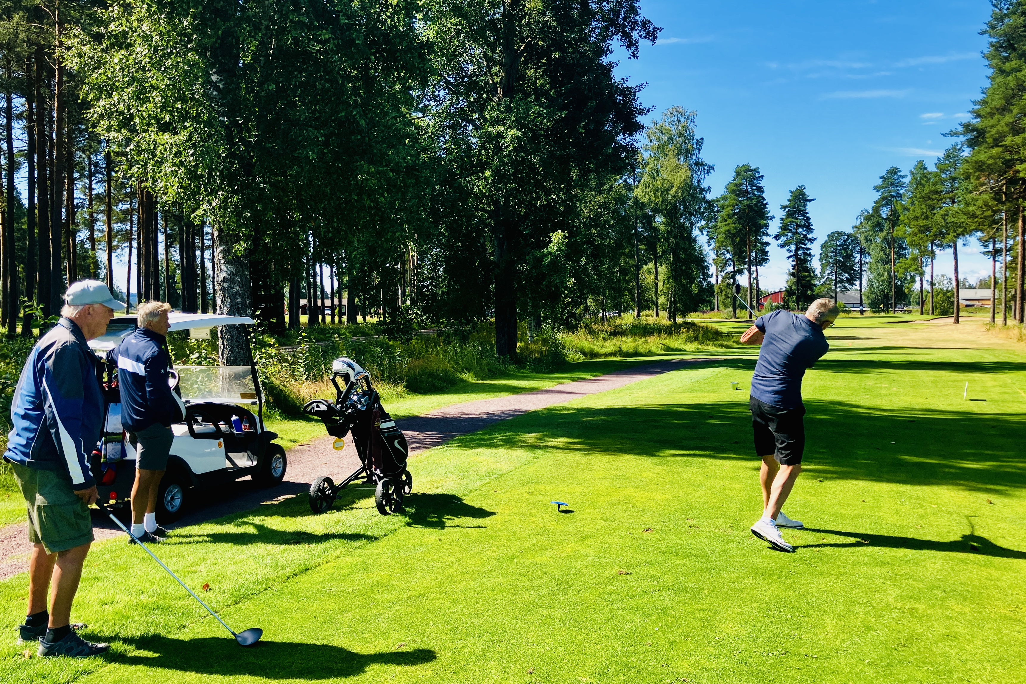 Lasse Larsson slår ut på hål 11 under överinseende av Åke Nalén och Mats Friberg