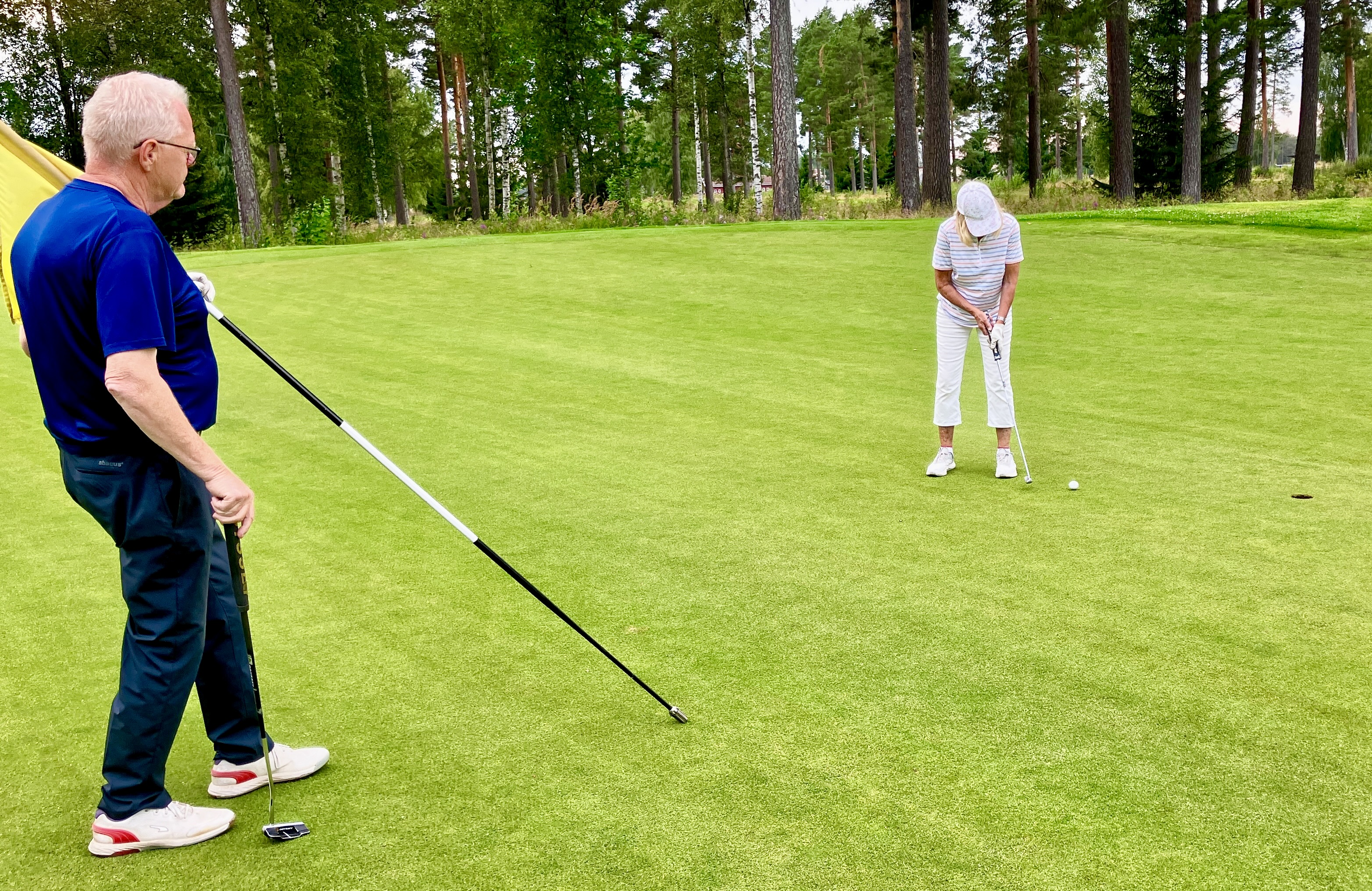 Eva Hindriks puttar på hål 15 under överinseende av Hans Bolmstam.