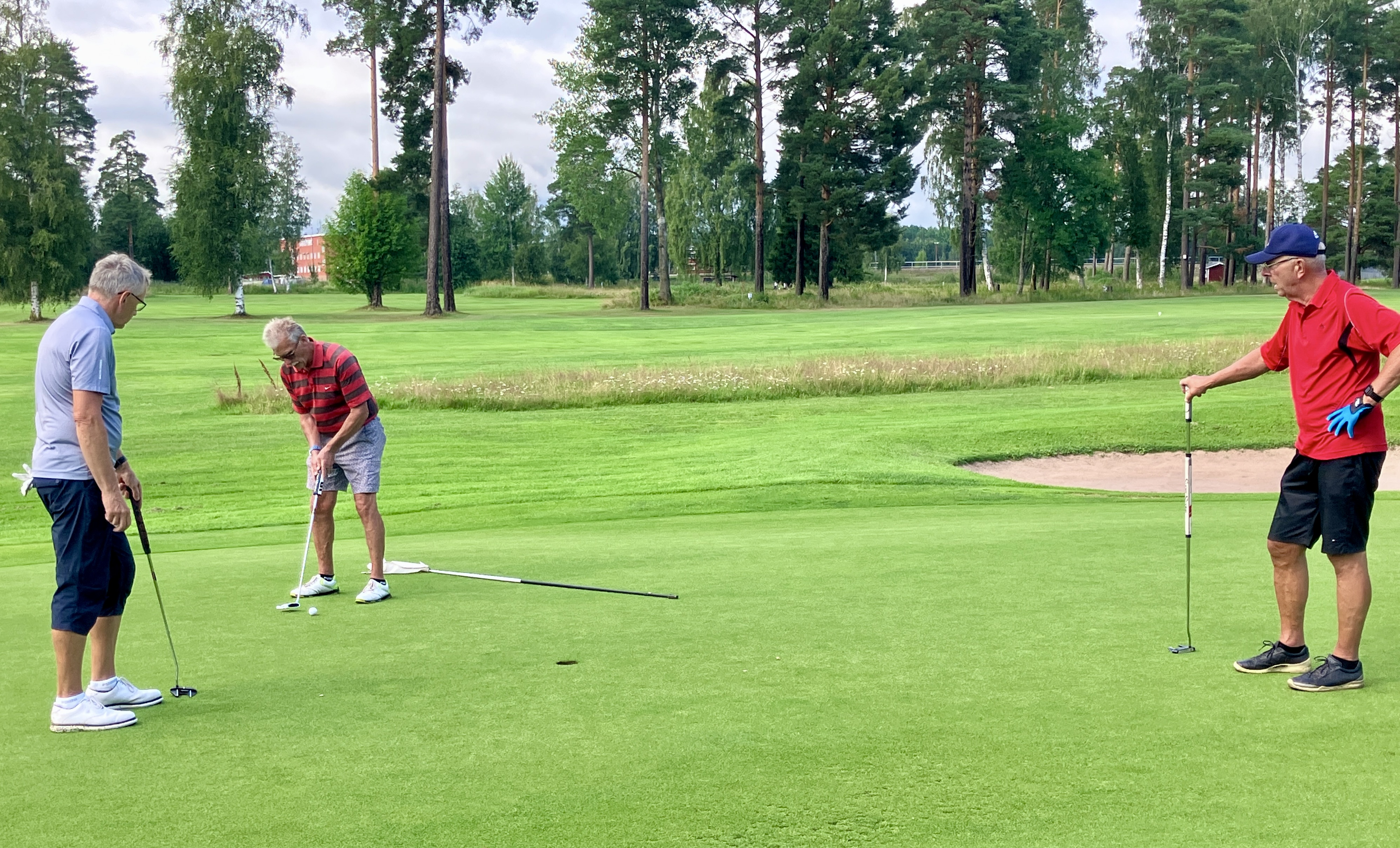 Bert Dyrén puttar på hål 14 medan Lasse Larsson och Hasse Ollas ser på.