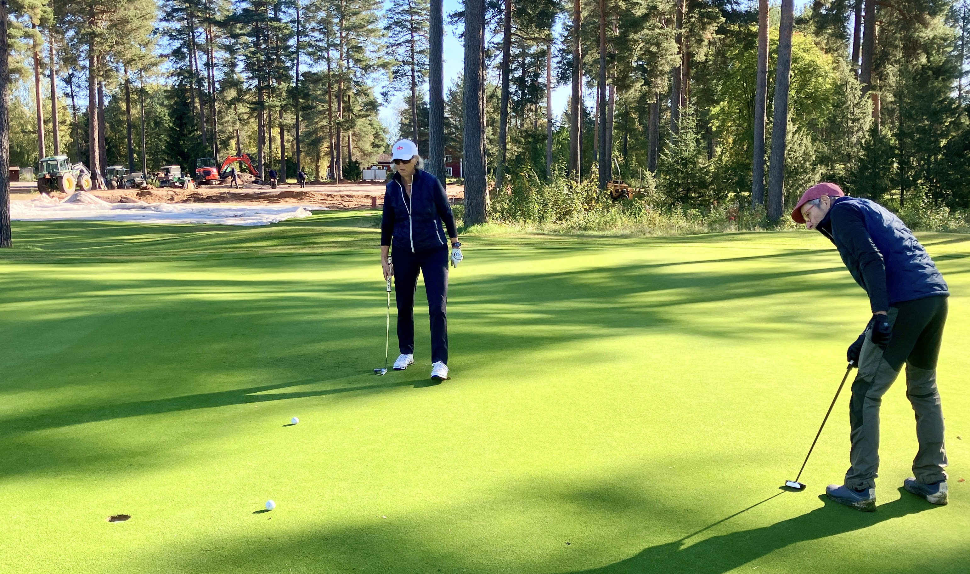 Leif Öyen puttar på hål 12 under överinseende av Lisa Kallur.