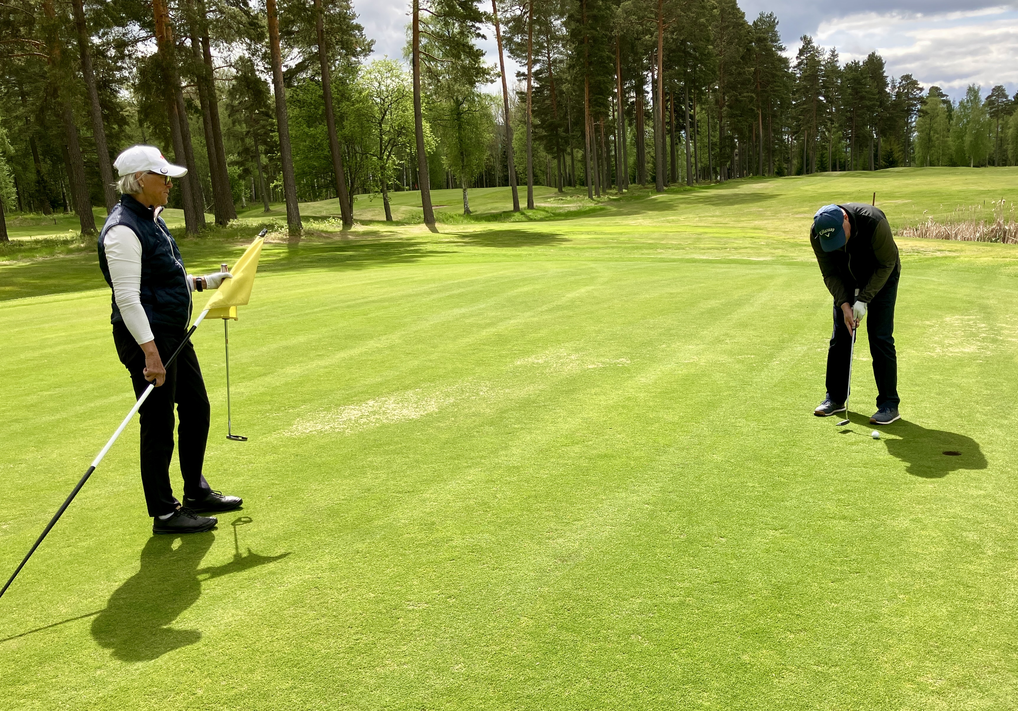 Trean Mikael Abelin slår i parputten på hål 17 under överinseende av Lisa Kallur.